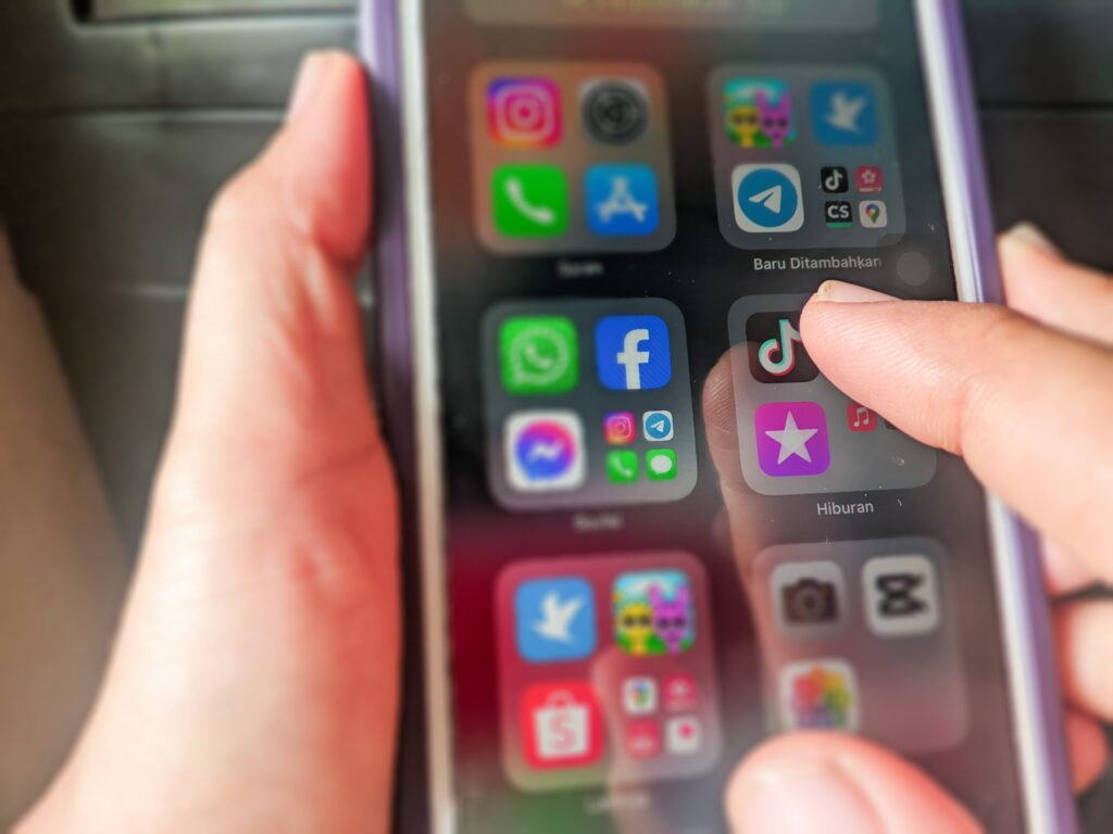 A,Hand,Is,Holding,An,Iphone,To,Open,The,Tiktok
